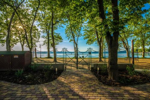 a fence with a tree in front of a lake at Hotel Anna Villa in Balatonföldvár