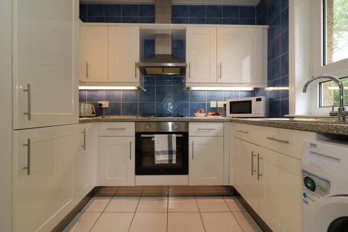 a kitchen with white cabinets and a stove top oven at Signature - Shawburn House in Hamilton