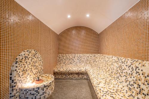 a bathroom with a tub in a tiled wall at Park Hotel Asenevtsi in Veliko Tŭrnovo