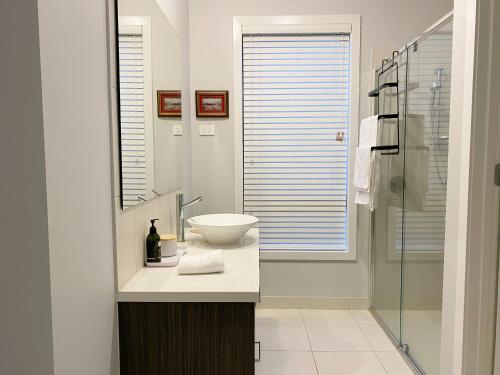 uma casa de banho com um lavatório e uma cabina de duche em vidro. em DnF House in Williams Landing em Laverton