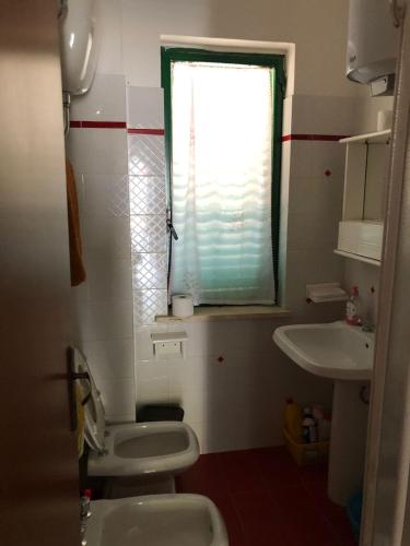 a bathroom with a toilet and a sink and a window at La Terrazza sul Mare in Sellia Marina