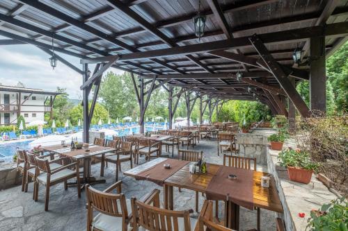 an outdoor patio with tables and chairs and a pool at Park Hotel Asenevtsi in Veliko Tŭrnovo