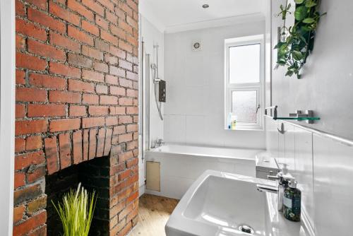 a bathroom with a brick fireplace and a sink at Comfortable 2 Bedroom Flat Overlooking the park in Bristol