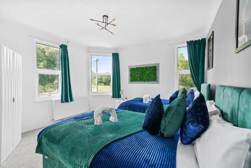 a bedroom with two beds with blue and green pillows at Comfortable 2 Bedroom Flat Overlooking the park in Bristol