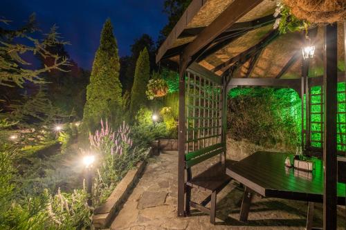 a pergola with a bench in a garden at night at Park Hotel Asenevtsi in Veliko Tŭrnovo