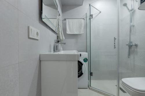 a white bathroom with a washing machine and a shower at The SPOT apartments - Orbi Beach Tower in Batumi