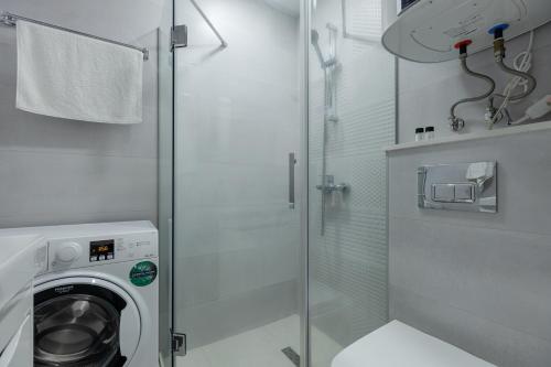a bathroom with a washing machine and a glass shower at The SPOT apartments - Orbi Beach Tower in Batumi
