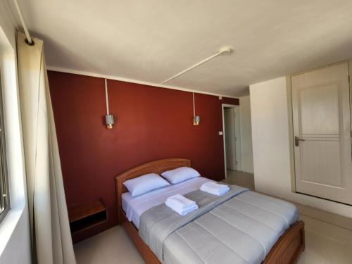 een slaapkamer met een bed met witte lakens en een rode muur bij Sunsetview Beach Apartment in Palmyre