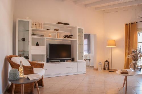 a living room with a tv on a white cabinet at Adorable Country House with sea & church view! in Kokkini Khanion