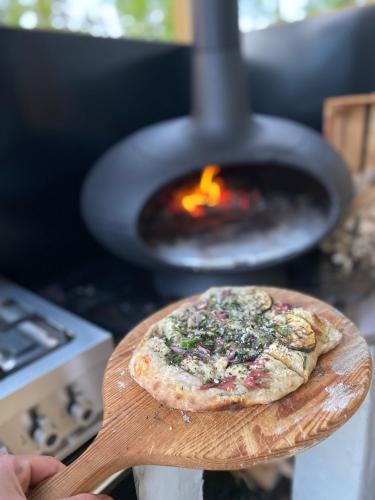 a person holding a pizza on a wooden paddle with a fire oven at Eremitstuga Detox resort in Köpmannebro