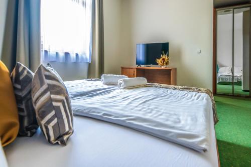 a large white bed in a room with a television at Hotel Anna Villa in Balatonföldvár