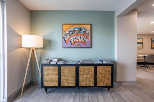 einen Tisch mit einer Lampe und ein Gemälde an der Wand in der Unterkunft The Windstar Hotel - Carolina Beach in Carolina Beach