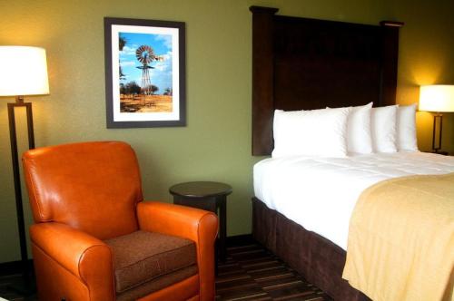 a hotel room with a bed and a chair at Comfort Inn & Suites in Beeville