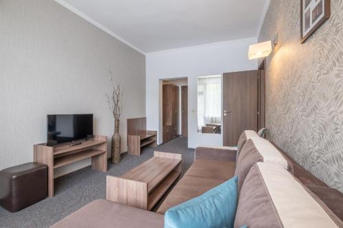 a living room with a couch and a tv at Park Hotel Asenevtsi in Veliko Tŭrnovo