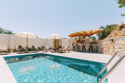 Una piscina con sillas y sombrillas al lado de una casa. en Stavlos Luxury Stone House, en Ialisos