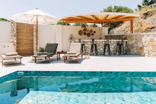 patio z basenem, stołem i krzesłami w obiekcie Stavlos Luxury Stone House w mieście Jalisos