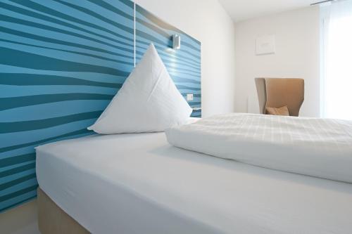 sypialnia z białym łóżkiem i niebieską ścianą w obiekcie east Apart w mieście Erlangen