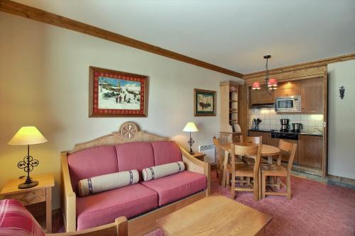 un salon avec un canapé rouge et une cuisine dans l'établissement ARC 1950 - Suite de Prestige - Cheminée intérieur, à Arc 1950