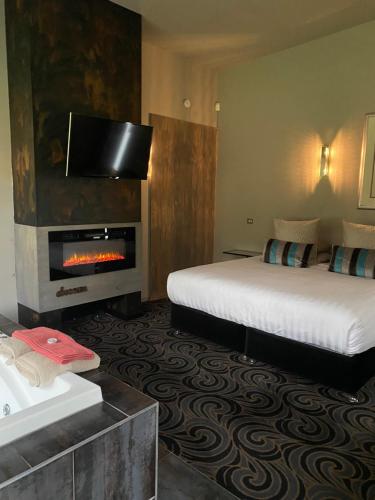 a hotel room with a bed and a fireplace at Spa Suites at RAVEN in Hepburn Springs