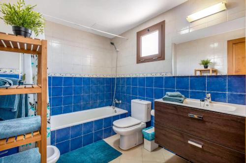 Baño azul con aseo, bañera y lavamanos en Modern house in Puerto del Carmen, en Tías