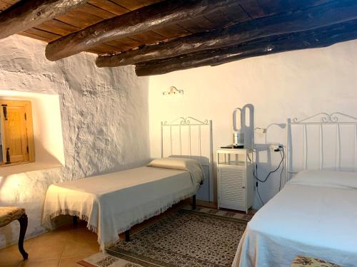 2 camas en una habitación con paredes blancas en La Cabieda - Junto al Río Cañamares - ideal para grupos y familias, en Chilluévar