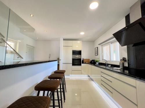 a kitchen with bar stools and a counter top at Albufeira Deluxe Residence With Pool by Homing in Albufeira