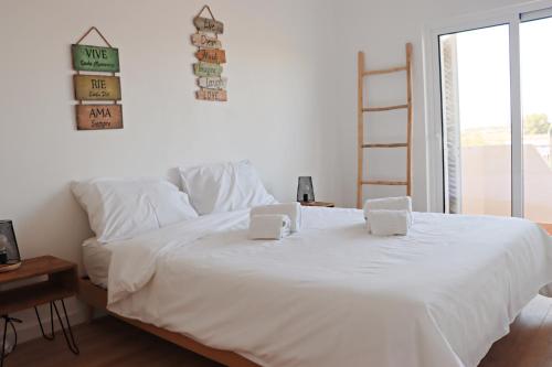 1 dormitorio con 1 cama blanca y 2 almohadas en Vivenda Geminada com piscina a 10 minutos a pé da praia, en Portimão