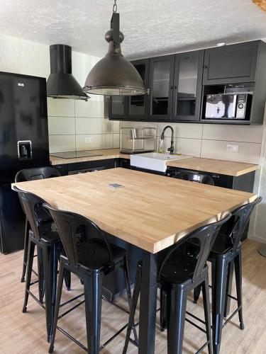 une cuisine avec une table en bois et des chaises noires dans l'établissement Bas de chalet au pied des pistes Cambre d'aze, à Saint-Pierre-dels-Forcats