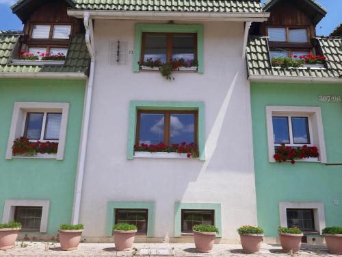 un edificio blanco con macetas de flores delante de él en Villa Vraji en Hrabušice