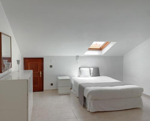 um quarto branco com uma cama e um lavatório em Supertubos Beach Villa em Atouguia da Baleia