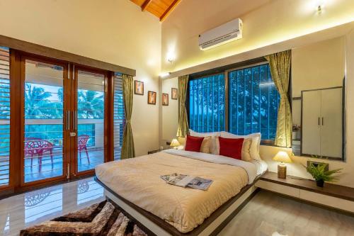 a bedroom with a large bed and large windows at Coco Palms by VEO - Part of StayVista in Nashik