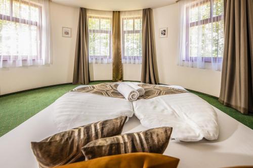 a large bed in a room with windows at Hotel Anna Villa in Balatonföldvár