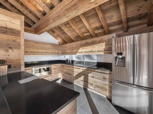 Il comprend une cuisine avec un réfrigérateur en acier inoxydable et des murs en bois. dans l'établissement Chalet moderne à Méribel avec jacuzzi, sauna, près des pistes et commerces - FR-1-566-30, à Les Allues