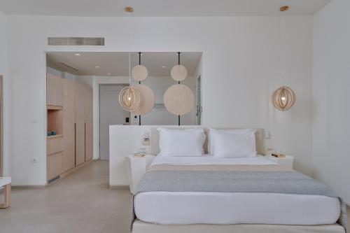 a white bedroom with a large bed and some lights at Meltemi Blu - Adults Only in Perissa