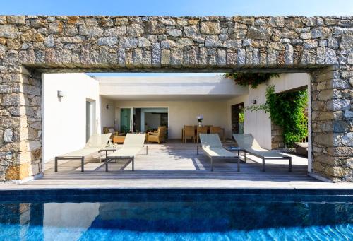 a house with a swimming pool and a stone wall at VILLA CALA ROSSA in LʼÎle-Rousse