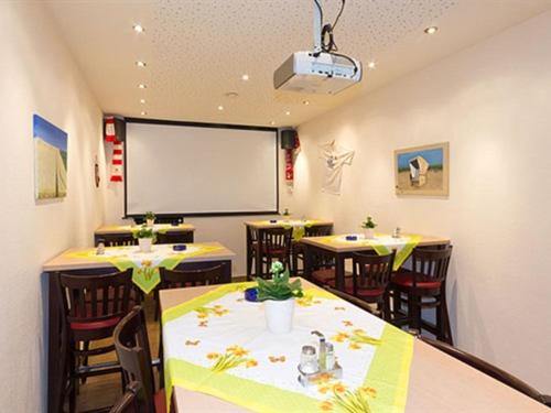 une salle de conférence avec des tables et des chaises et un tableau blanc dans l'établissement Hotel Fassbender, à Pulheim
