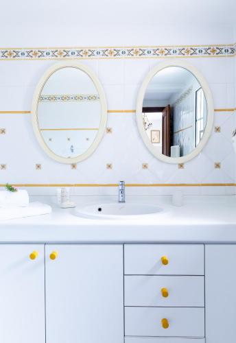 - une salle de bains blanche avec deux miroirs et un lavabo dans l'établissement VILLA CALA ROSSA, à LʼÎle-Rousse