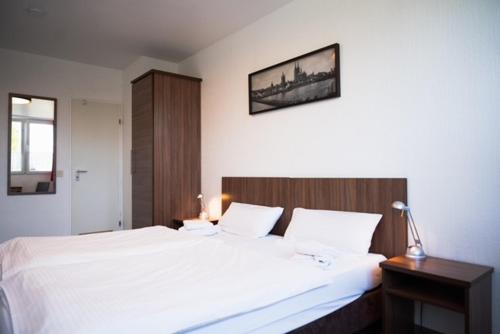 a bedroom with a large white bed with a wooden headboard at Hotel Fassbender in Pulheim