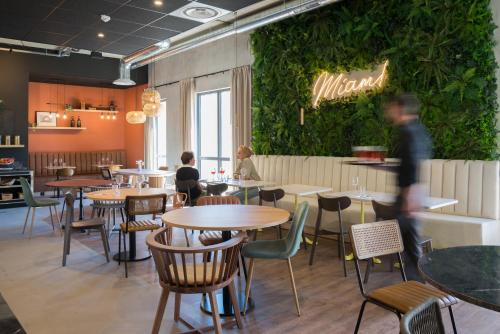 Un restaurante con mesas y sillas y una pared verde. en Campanile Saint Brieuc - Centre Gare, en Saint-Brieuc