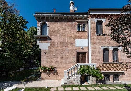 a red brick building with a staircase in front of it at Villa Gallo 1915, luxurious villa with garden and SPA in Venice-Lido