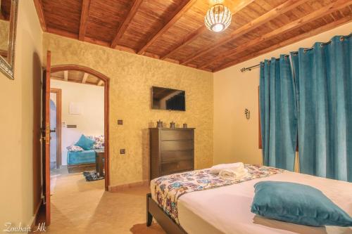 a bedroom with a bed with blue curtains and a mirror at villa Rita chaouen in Chefchaouen