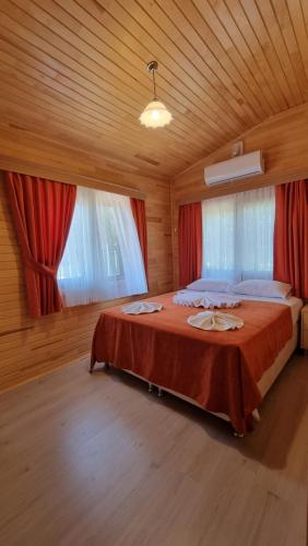 a bedroom with a large bed with red curtains at Villa Efsane Hotel in Cıralı