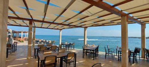 um restaurante com mesas e cadeiras e o oceano em Aquarius Touristic Resort em Al Minyah