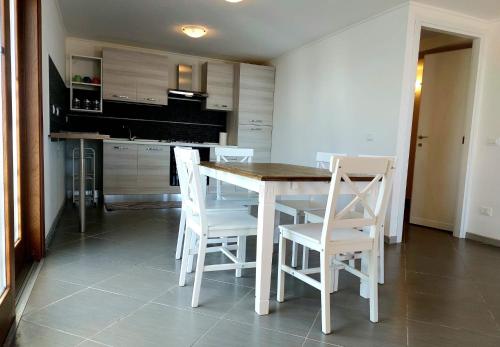 a kitchen with a table and white chairs in it at JAZZ STYLE - On The Beach - Anzio in Anzio