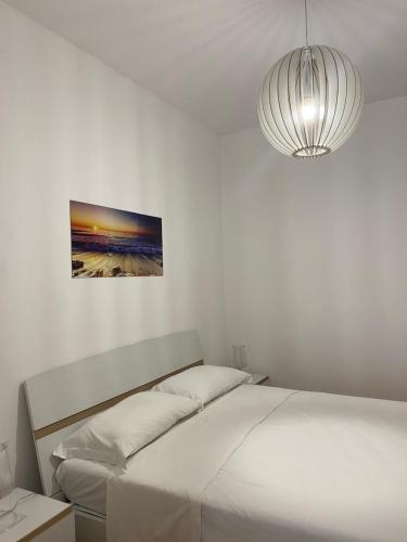 a white bedroom with a bed and a pendant light at Nova Lux in Custonaci