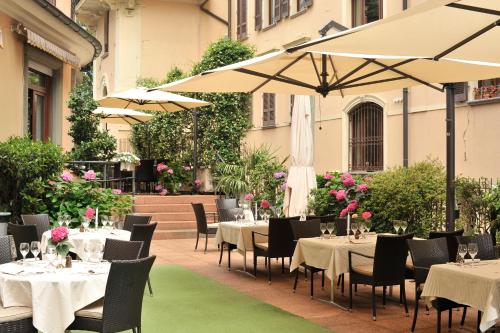 ein Restaurant mit Tischen, Stühlen und einem Sonnenschirm in der Unterkunft Hotel Federale in Lugano