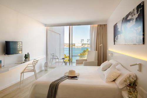 a hotel room with a bed with a view of the ocean at Els Pins Resort & Spa - Emar Hotels in San Antonio Bay