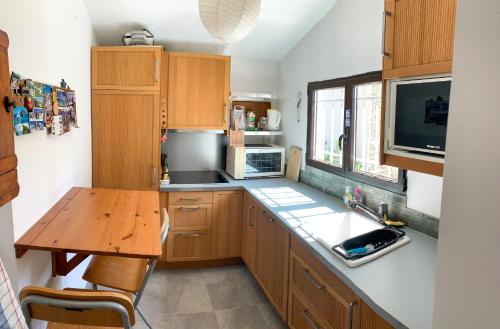- une cuisine avec des placards en bois, une table et un évier dans l'établissement Nuits magiques au village entre mer et montagnes, à Bigorno