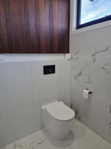 a bathroom with a toilet and a window at RESIDENTIAL 4 BEDROOM House in Coffs Harbour