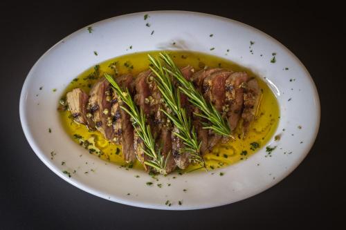 a plate with a piece of meat with rosemary on it at Agriturismo la campagnola in Gordona